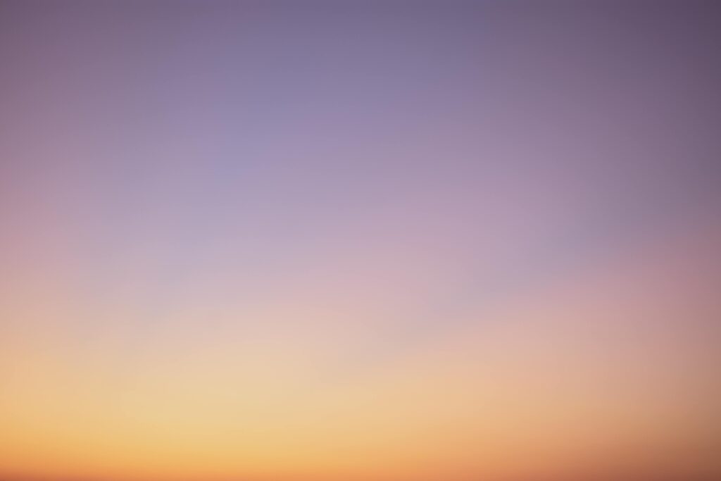 A serene gradient sky with hues of blue, pink, and orange during twilight.